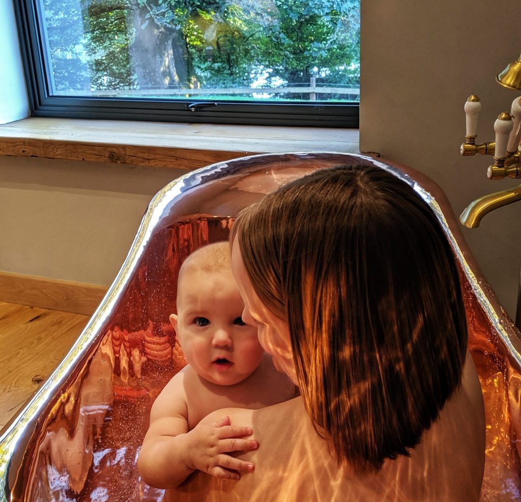 A lady with her child in a gleaming Copper Bathtub